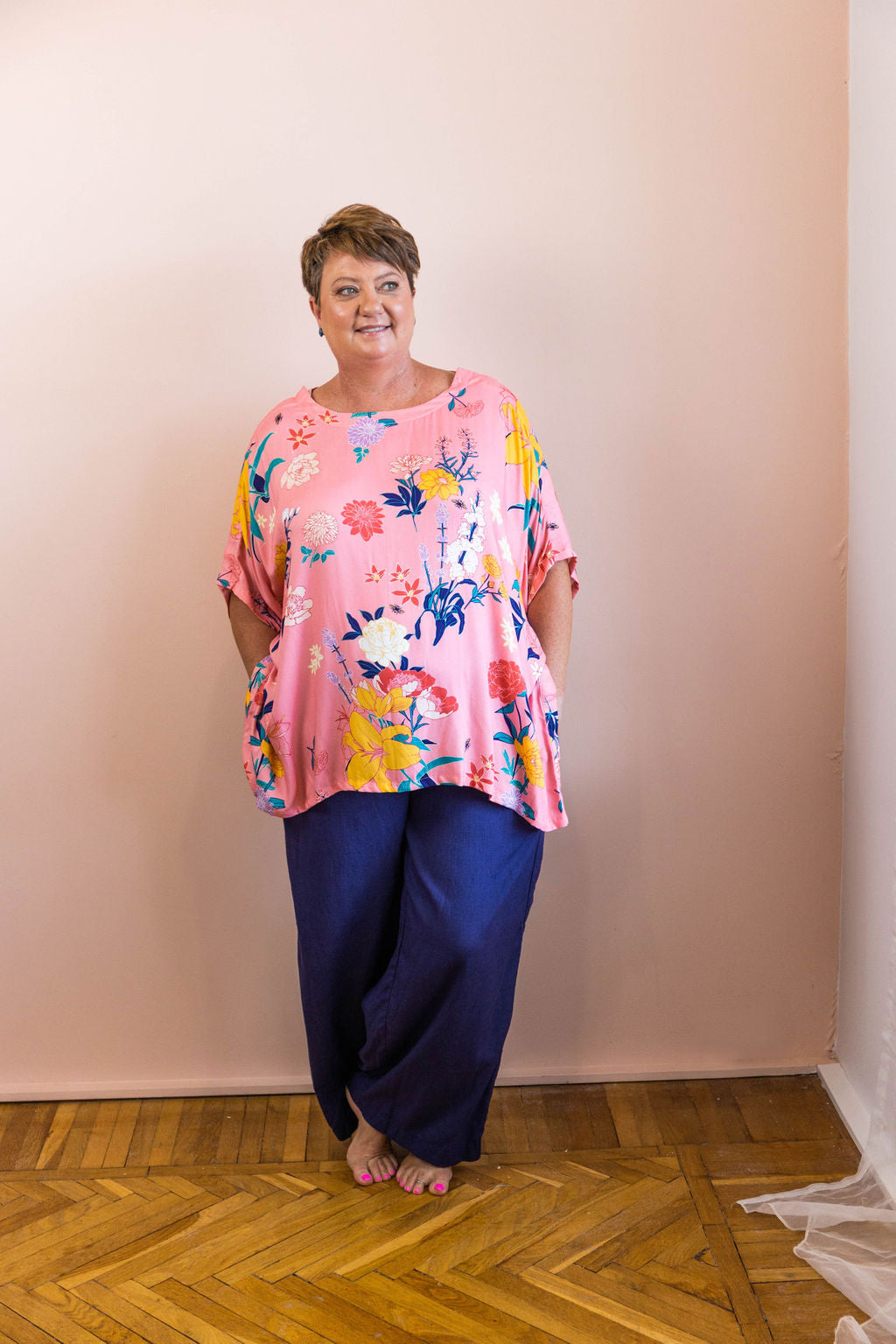 woman standing wearing pink floral fiorella adaptive top and navy linen adaptive pants