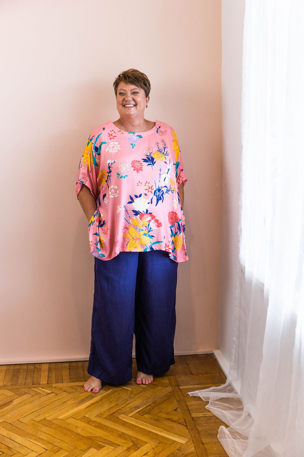 woman smiling wearing pink floral adaptive shirt and navy linen adaptive pants