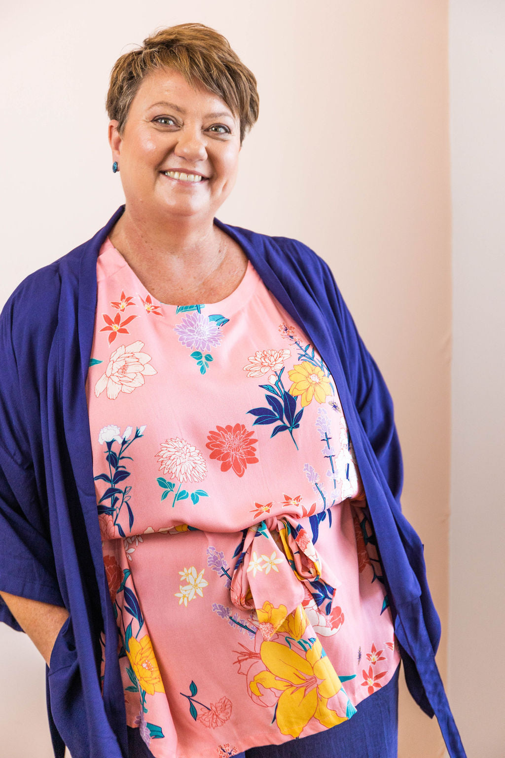 woman smiling wearing pink floral adaptive top and navy wrap top as a jacket