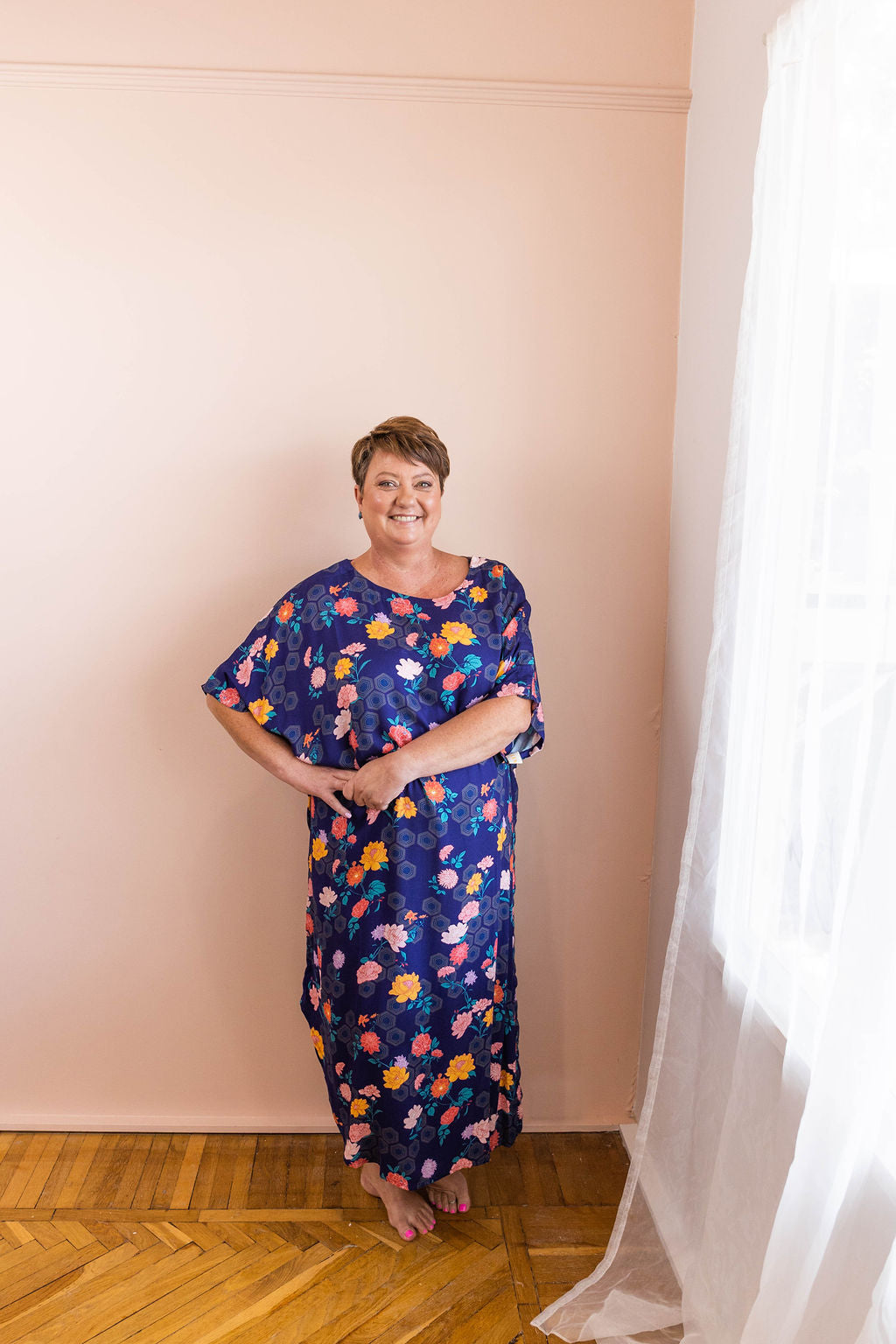 woman with her hands on her hips smiling in a navy geometrica floral print adaptive dress