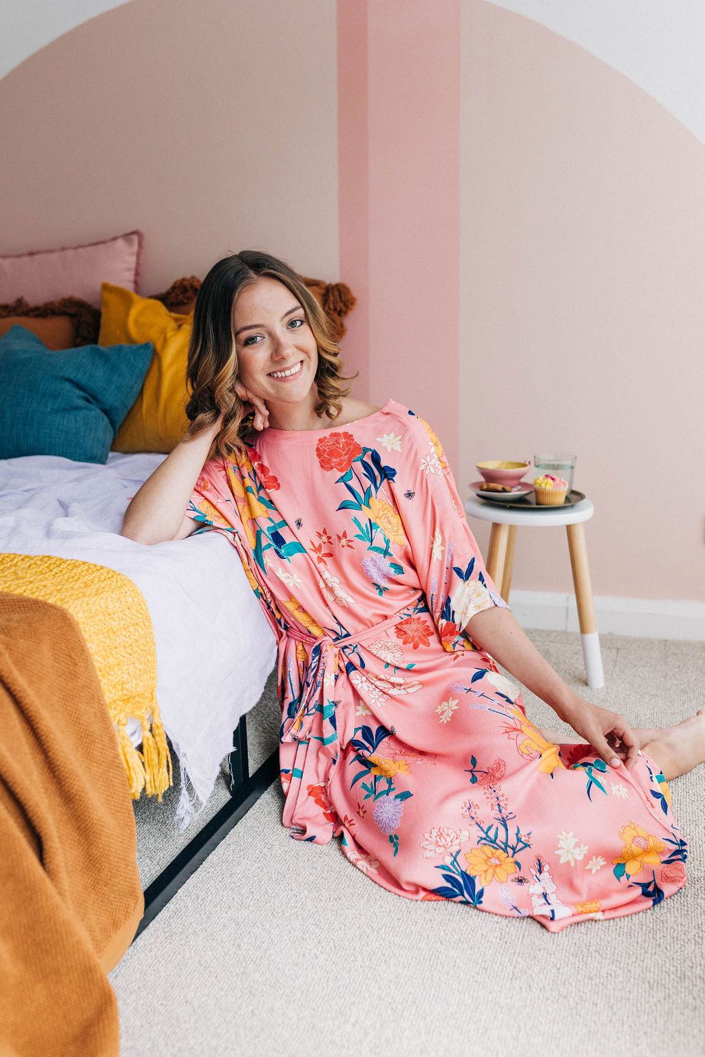 woman smiling sitting on the floor wearing a pink floral adaptive dress