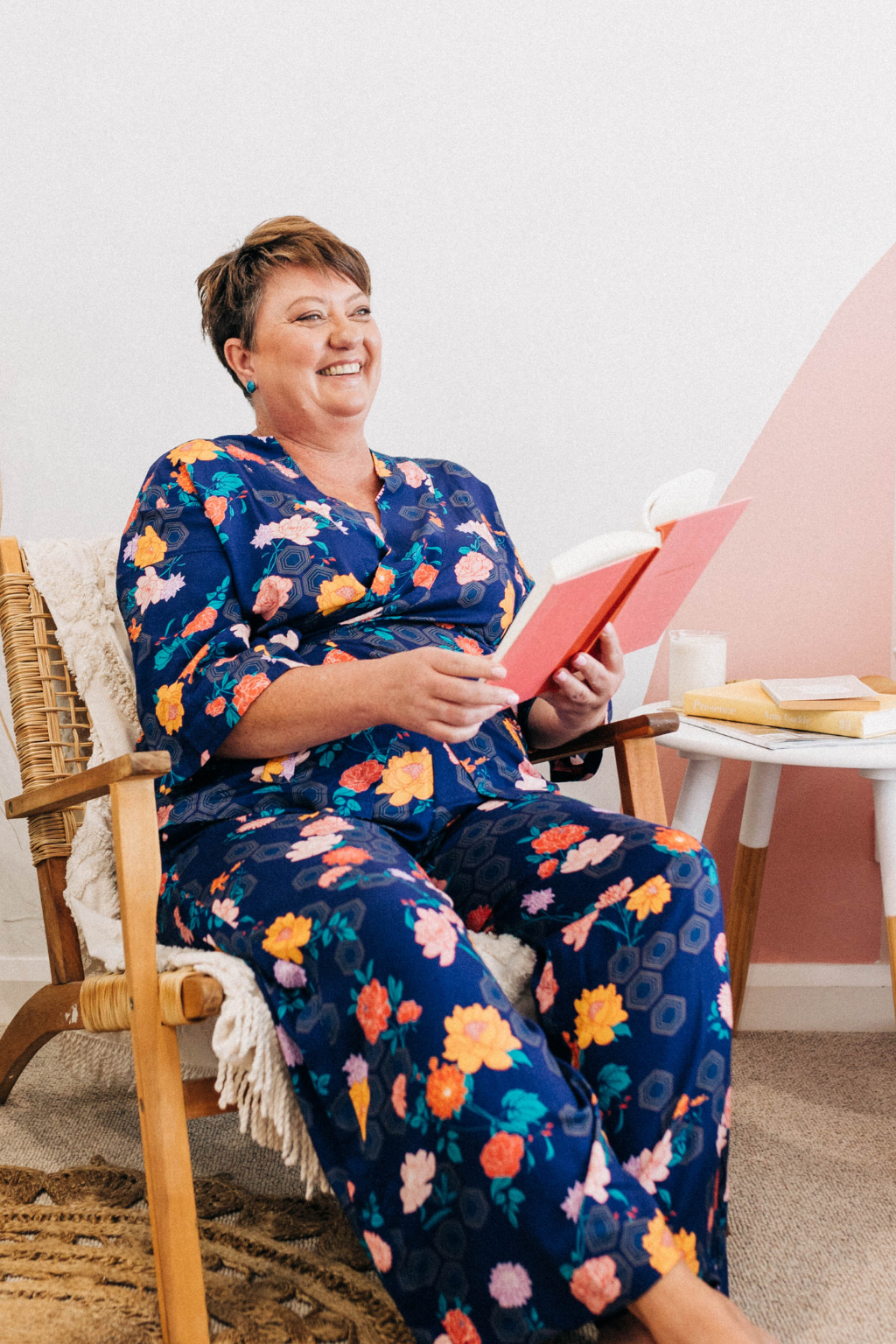 woman sitting in a chair reading a pink book wearing matching limonata adaptive print set in navy geometrica print with flowers and honeycomb hexagon print