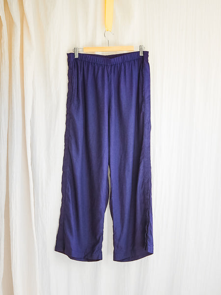 wide leg navy linen adaptive pants by limonata, hanging on a coathanger